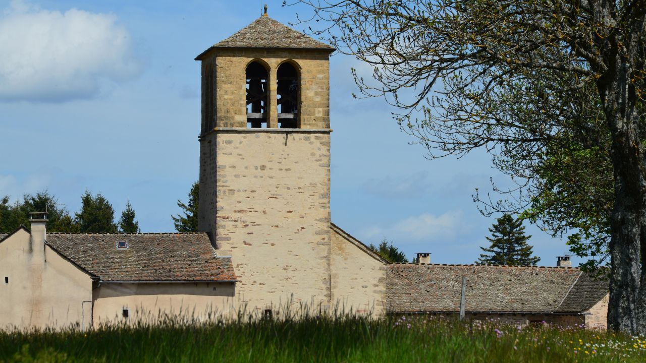 Historic stone church tower amid scenic Mont Lozère et Goulet, France landscape.