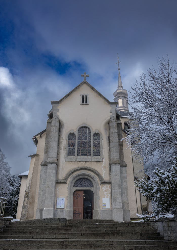 Baroque architecture of Saint Michel Church in snowy Chamonix, France with dramatic winter sky.